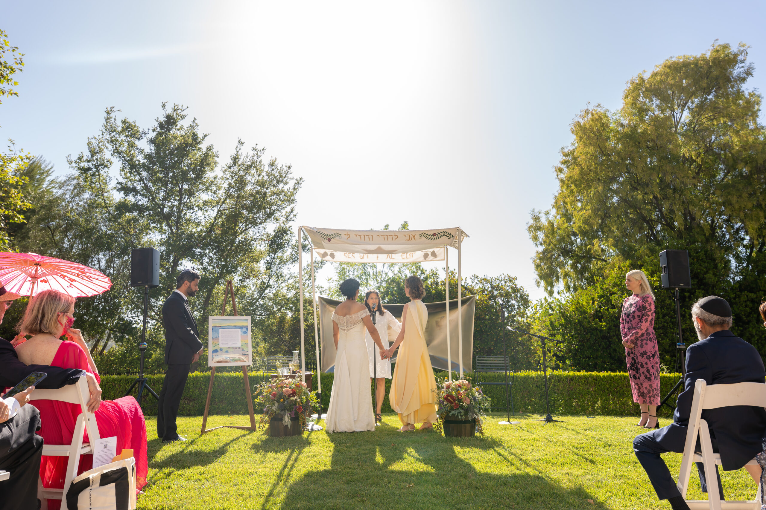 two brides stand together under the wedding chuppah