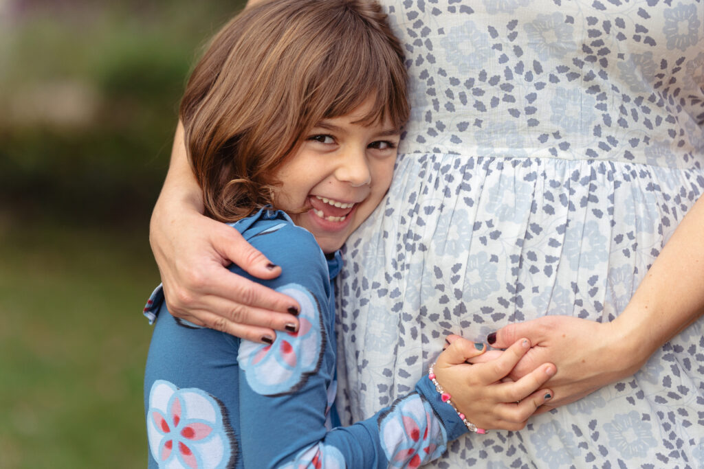 a young girl hugging her mom's pregnant belly