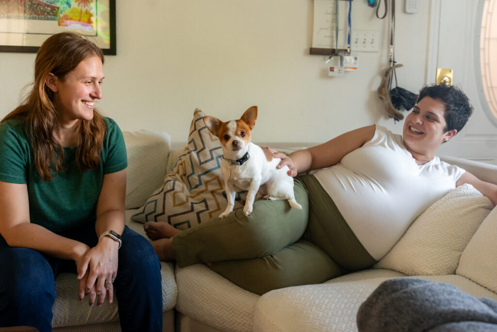 maternity session at home with two moms and their dog on the couch