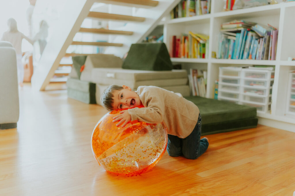 a boy on the floor with a giant orange ball