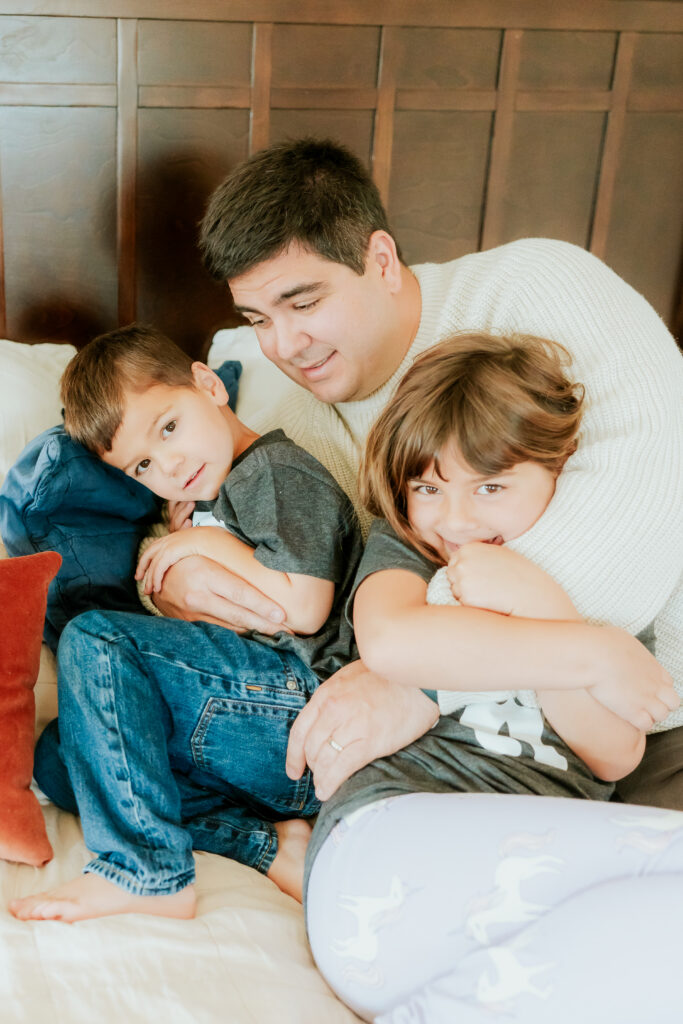dad hugging two kids on the bed