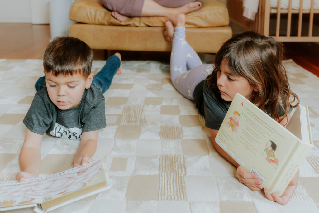 two kids laying on the floor reading books